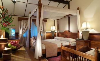 a large bed with a canopy is in the middle of a room with a table and chairs at Lavilla by Holiday Villa Cherating