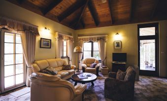 a cozy living room with two couches , a coffee table , and a television mounted on the wall at Holberry House