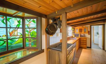 a kitchen with a wooden ceiling and floor , a stove , and a window with a stained glass design at Bruny Island Escapes and Hotel Bruny