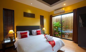 a bedroom with a large bed and white sheets , red pillows , and a glass door leading to a garden at Chalicha Resort