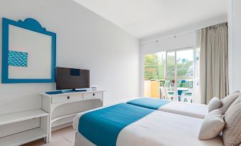 a modern bedroom with white walls , blue bedspread , and tv on a white dresser , next to a sliding glass door leading to an outdoor at Bluesea Costa Verde