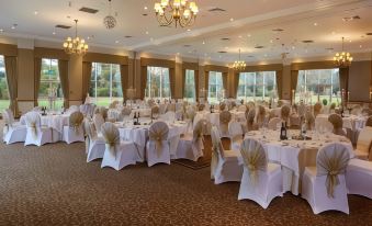 a large banquet hall filled with tables and chairs , ready for a formal event or a wedding reception at Macdonald Craxton Wood Hotel