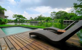 a wooden deck overlooking a body of water , with two lounge chairs placed on the deck for relaxation at The Westlake Hotel & Resort Yogyakarta