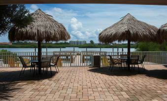 a patio with two thatched - roof umbrellas , chairs , and tables overlooks a lake and cityscape at Legacy Vacation Resorts-Indian Shores