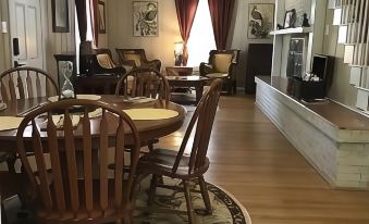 a large dining room with wooden chairs and a table , situated in a house with hardwood floors at Sassafras Inn
