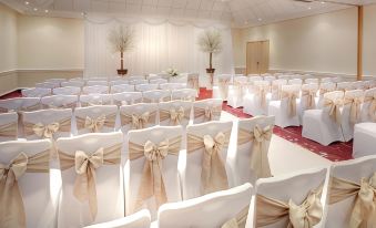 a large banquet hall with rows of white chairs and beige bows on the backs at DoubleTree by Hilton Manchester Airport