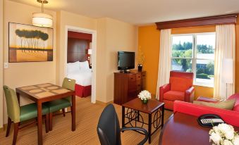 a hotel room with a living area , dining table , chairs , couch , television , and a bed at Residence Inn Auburn