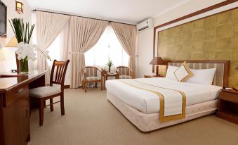 a large bed with white linens and gold accents is in a room with two chairs , lamps , and windows at Palace Hotel