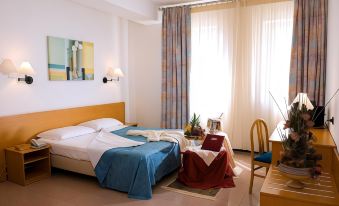 a hotel room with a double bed , a chair , a tv , and a dining table at Hotel Astoria