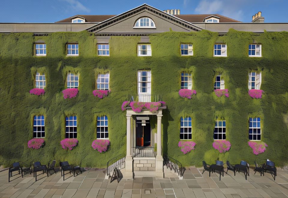 a large green building with pink flowers hanging from the windows , creating a unique and eye - catching design at Angel Hotel