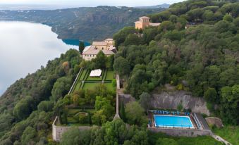 an aerial view of a large villa surrounded by trees , with a swimming pool in the foreground at Villa Palazzola