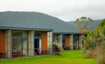 a row of small , modern houses with orange and blue accents are situated on a grassy field at Sunset Motel