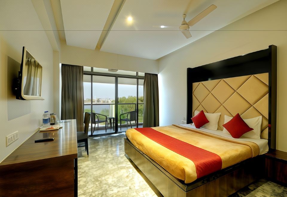 a hotel room with a king - sized bed , a desk , and a large window overlooking a lake at Hotel Apaar