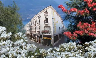 a large white building with flowers in front of it , surrounded by mountains and trees at PRIMAVERA