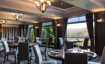 a restaurant with large windows offering a view of the mountains , tables set for dining , and chairs at Beech Hill Hotel & Spa