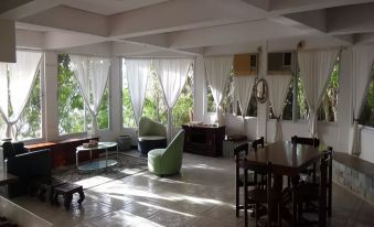 a modern living room with white walls , large windows , and wooden floors , featuring comfortable seating arrangements and dining area at Bantayan Island Nature Park and Resort