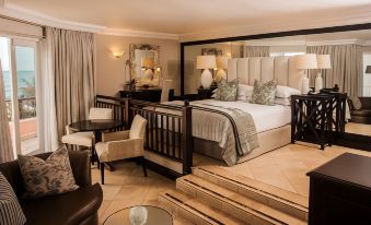 a luxurious hotel room with a large bed , a chair , and a mirror on the wall at Beverly Hills