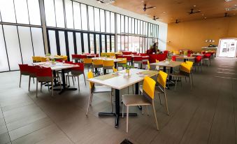 a large dining room with multiple tables and chairs , some of which are red and yellow at Lakeview Terrace Resort Pengerang