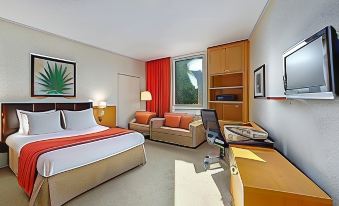 a hotel room with a bed , couch , desk , and window , decorated with modern furniture and artwork at NH Luxembourg