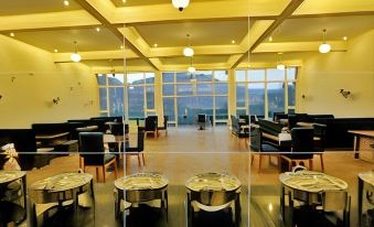 a modern restaurant with large windows , black leather chairs , and wooden tables set for dining at River Rock Resort