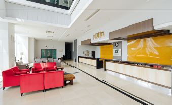 a modern hotel lobby with a reception desk , red couches , and a large window offering views of the city at Raia Hotel & Convention Centre Alor Setar