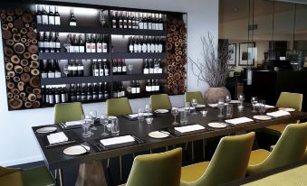 a modern restaurant with a long dining table set for a meal , surrounded by chairs and a wine rack at Mercure Clear Mountain Lodge