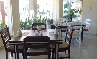 a restaurant with wooden tables and chairs , white napkins on the tables , and large windows at Khas Parapat