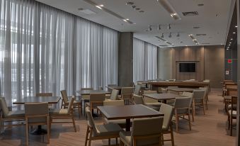 a modern conference room with wooden tables and chairs , large windows , and a flat screen tv at JL Hotel by Bourbon