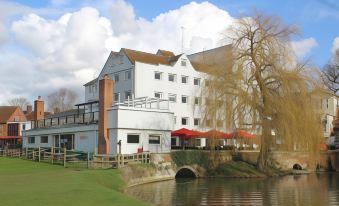 a large white building with a bridge in front of it , surrounded by trees and grass at The Mill Hotel