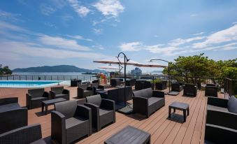 a rooftop lounge area with black chairs and tables , surrounded by a wooden deck and a view of the ocean at Todaya