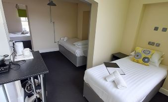 a hotel room with two beds , one of which is made up and has a laptop on it at Potbank