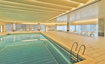 The hotel features an indoor swimming pool with a large window that offers views of the water and other rooms at Parsian Azadi Hotel