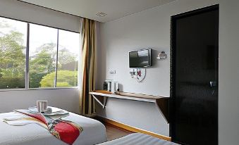 a hotel room with two beds , a desk , and a television mounted on the wall at AYANA Holiday Resort