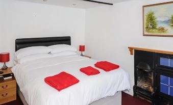 a white bedroom with a black bed , red sheets , and a fireplace next to the bed at George Inn