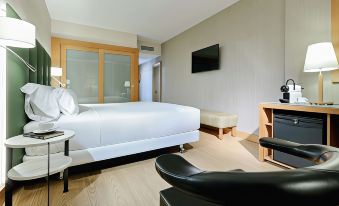 a hotel room with a king - sized bed , a flat - screen tv , and a chair in the corner at Hesperia Barcelona Sant Just