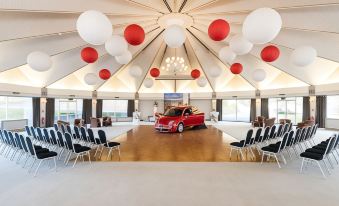 a room with a large white and red car parked under a tent , surrounded by chairs and tables at The Atholl Palace