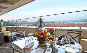 a dining table set with a variety of fruits , including apples , oranges , and bananas , as well as various utensils like forks at Divan Istanbul
