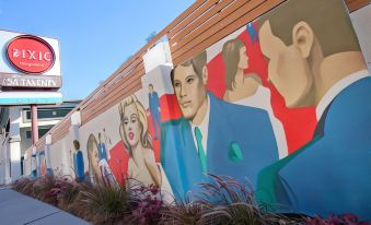 a colorful mural on the side of a building , with various people depicted in various poses and settings at The Dixie Hollywood