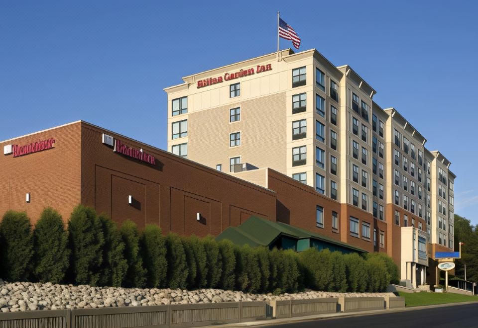 a hilton garden inn hotel with its sign and american flag on top of a building at Hilton Garden Inn Troy