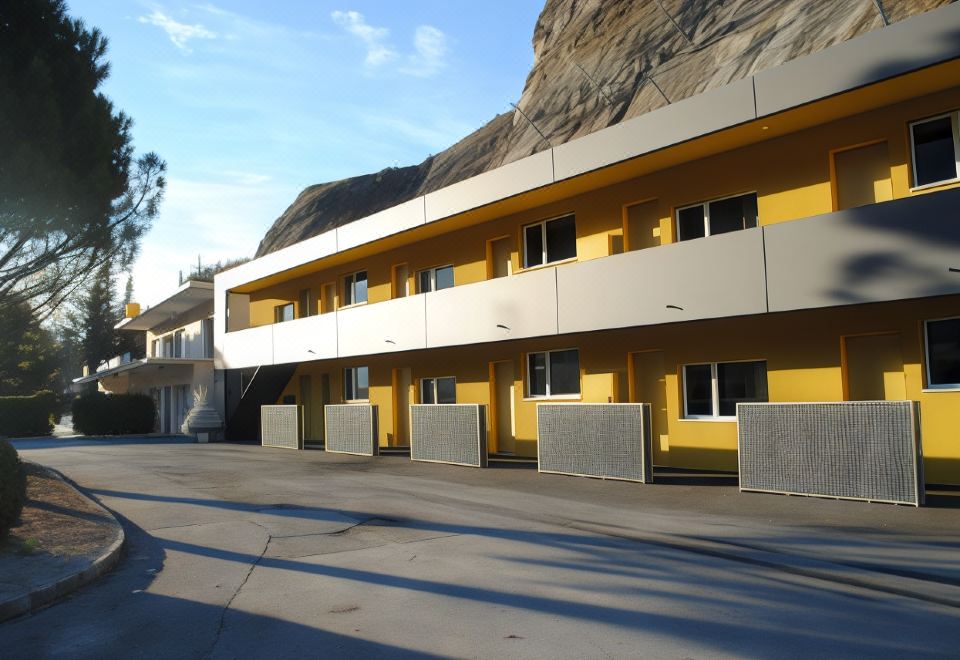 a yellow and white apartment building with a staircase leading up to it , situated in front of a mountain at Hotel du Soleil