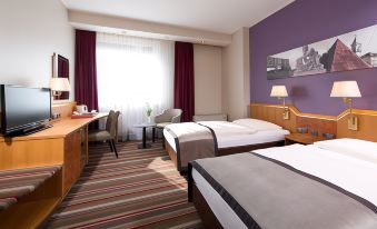 a hotel room with two beds , a desk , and a chair , along with curtains and a purple wall at Leonardo Hotel Karlsruhe