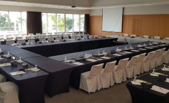 a conference room set up for a meeting , with multiple tables and chairs arranged in a semicircle at Chateau Royal Beach Resort & Spa, Noumea