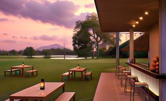 a well - lit outdoor dining area with wooden tables and benches , surrounded by a green grassy field at Jetwing Lake