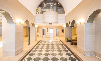 a grand foyer with a checkered floor , white walls , and arched enclosures , as well as two large domes on either side at Art Hotel Miyazaki Sky Tower