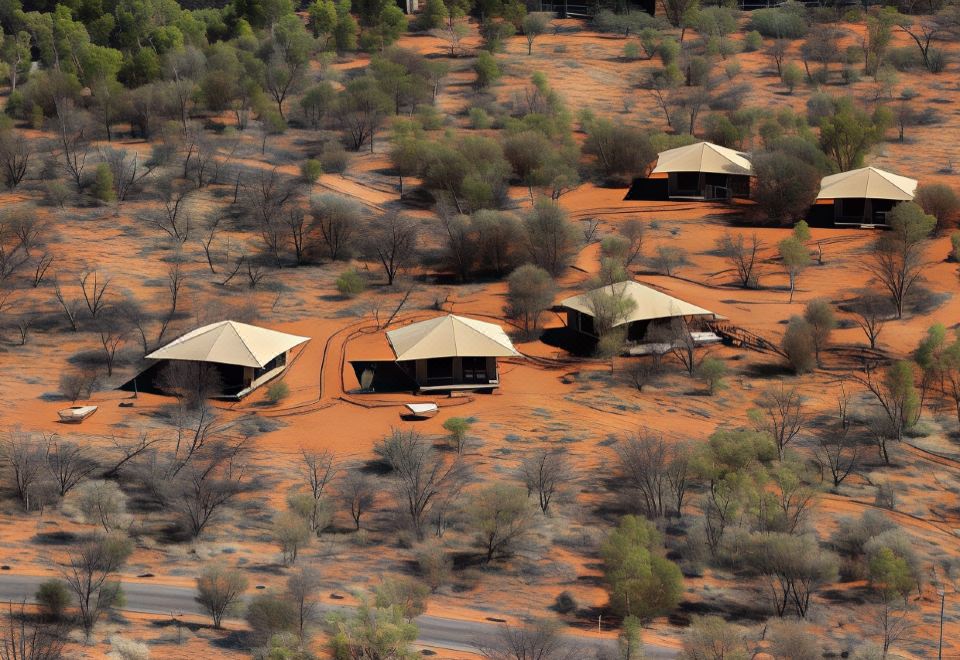 a group of tents are set up in a desert - like area with trees and shrubs at Discovery Resorts - Kings Canyon