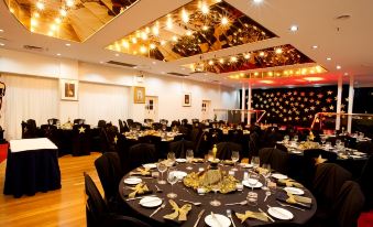 a well - decorated banquet hall with tables set for a formal event , including gold decorations and black tablecloths at Mercure Maitland Monte Pio