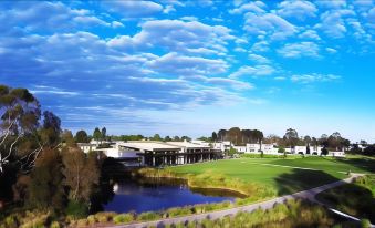 a beautiful landscape with a golf course , a pond , and a building under a cloudy sky at Lake Wendouree Luxury Apartments