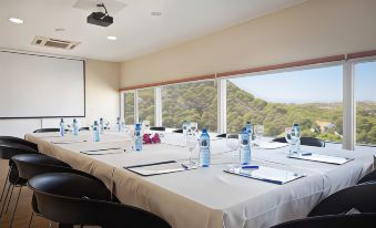 a conference room with a long table set up for a meeting , featuring white tablecloths and multiple chairs at Hotel Maya Alicante