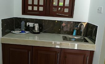a small kitchen with dark wood cabinets and a white countertop features a sink , trash can , and blue mouse at Sea Breeze