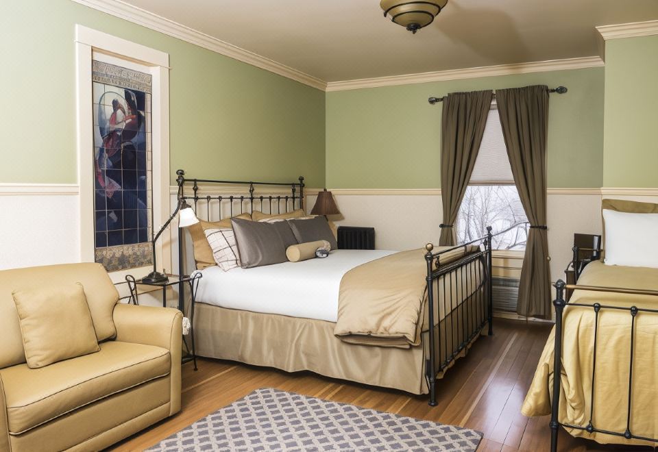 a spacious bedroom with a large bed , a couch , and a rug on the hardwood floor at Chamberlin Inn